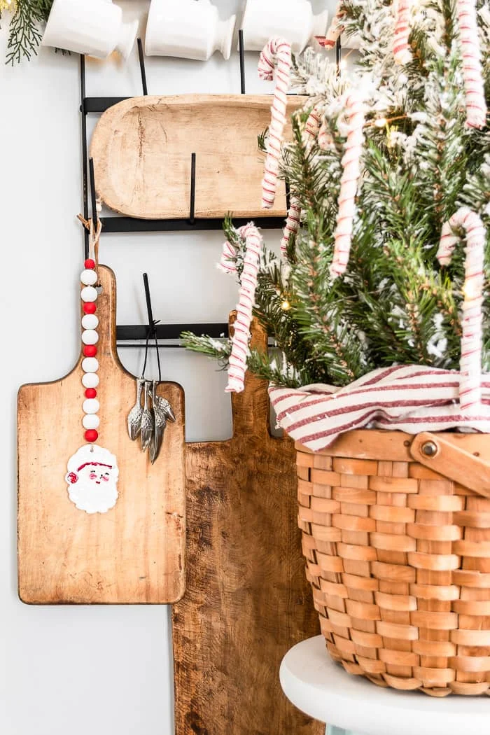 kitchen tree in basket with candy cane ornaments, wood cutting boards, Santa mugs, acorn measuring cups