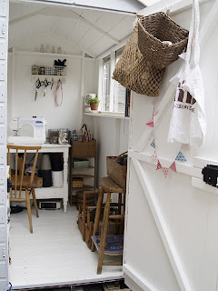 Inside the shed a desk, sewing machine and other work items