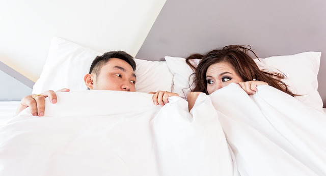 Couple Peeking Out from Under the Covers