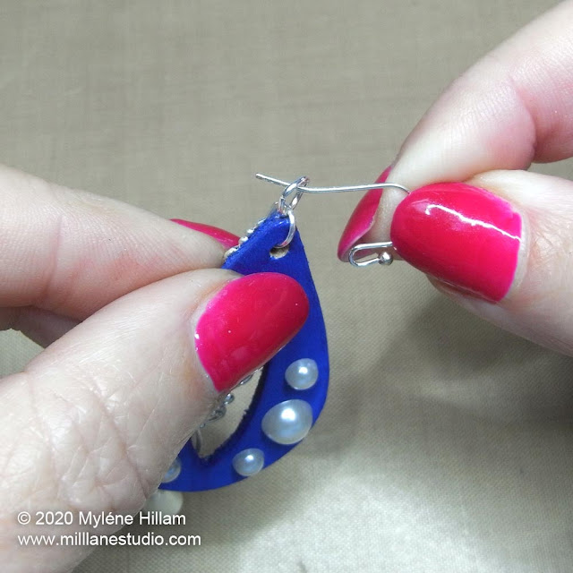 Inserting the earring wire through the jump ring at the top of the earring.