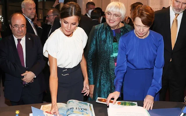 Queen Letizia wore a white silk blouse by Hugo Boss, and navy blue skirt by Boss. Elke Büdenbender wore a royal blue silk blouse