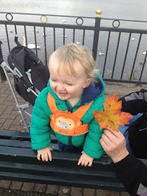 Toddler laughing whilst stood on park bench