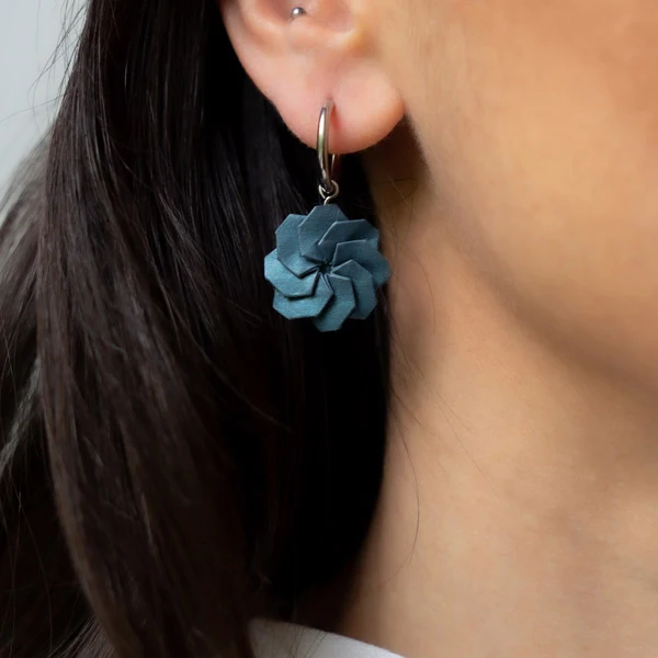 blue circular origami paper earring with silvertone hoop worn by model with long dark hair