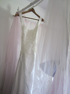 wedding dress hanging on bed