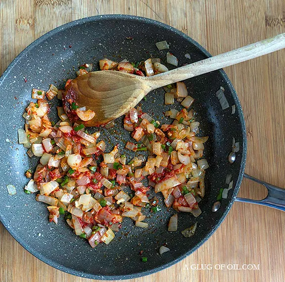 onions garlic and chill with tomato puree in a frying pan