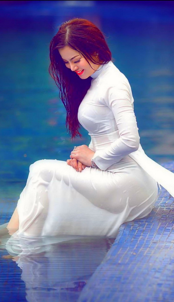 Thiếu nữ áo dài trắng ngồi bên hồ bơi