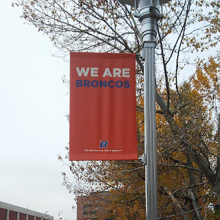 Orange banner on a light pole, with the words WE ARE BRONCOS