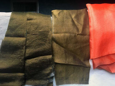 Three narrow strips of green-gold silk in a row, with bright peach silk at far right. The leftmost two strips show darker, because they're layered over grey linen, while the right strip is noticeably more gold, because it's layered over white linen.