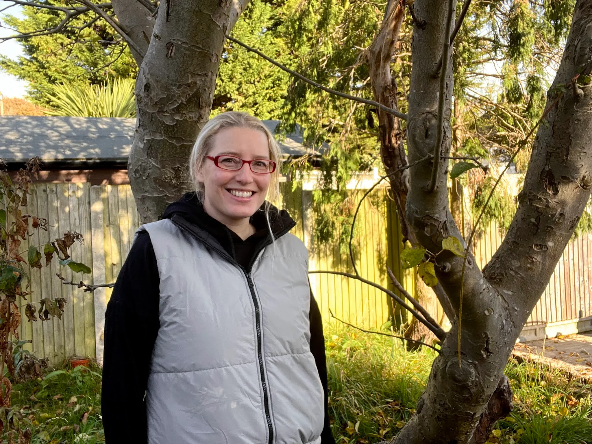 A mum standing looking cold in a grey reversible gillet and a black hoodie dress