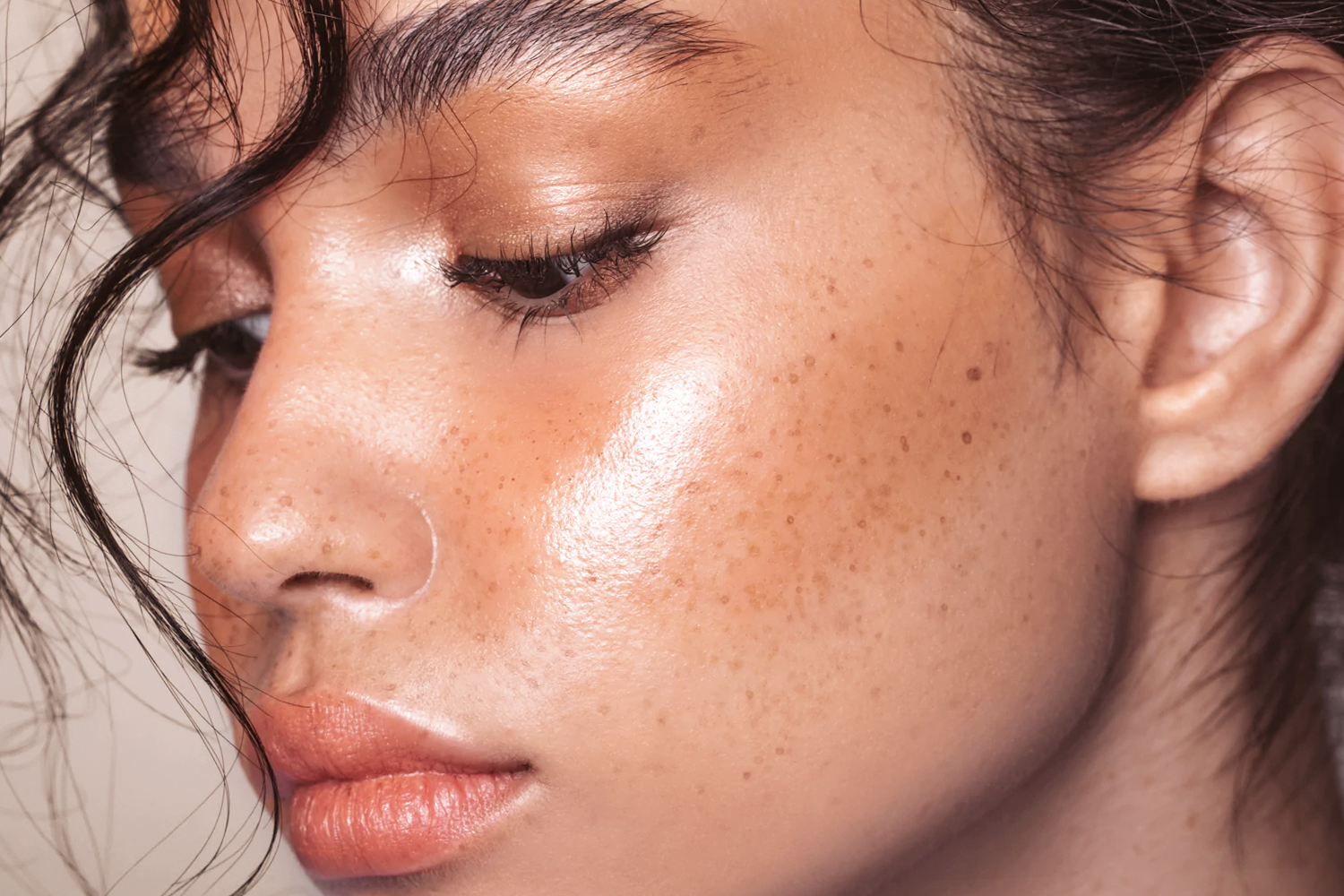 close-up beauty shot of a woman with dewy, clean girl makeup look and freckles on her face