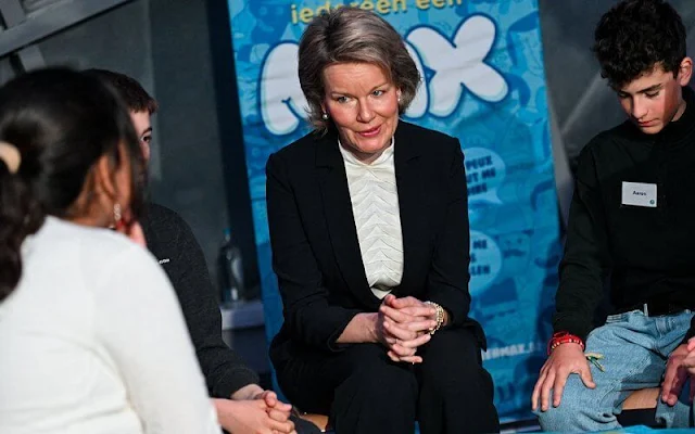 Queen Mathilde wore a dark green blazer pant suit by Armani. White silk blouse by Armani. Diamond earrings. Child Focus launched Max