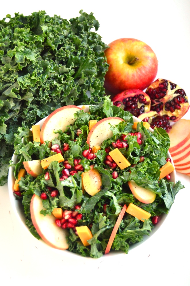 Kale Salad with Pomegranate, Cheddar and Apples features fresh kale, pomegranates, apples and cheddar cheese with a homemade apple cider vinaigrette for the perfect hearty salad! www.nutritionistreviews.com