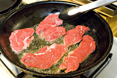 beef cutlets browning in pan