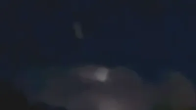 White rectangular shape object UFO flies up and out of the clouds during thunderstorm.