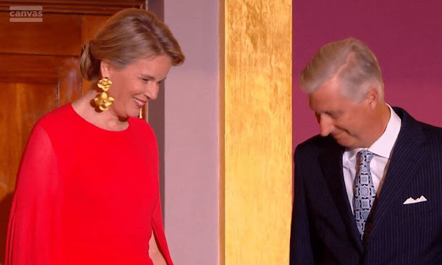 Queen Mathilde wore a new red cape-like sleeves maxi dress by Essentiel Antwerp. Christine Bekaert poppy small gold earrings