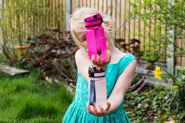 A girl holding one water bottle on top of the other blocking out her face