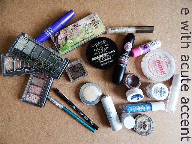 Messy flat lay of make up like lip gloss, powder, eyeshadow pallets and ey pencils