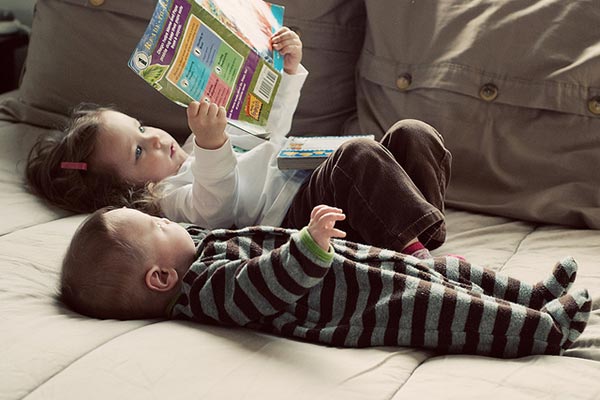 Una niña y un niño ojean un cuento.