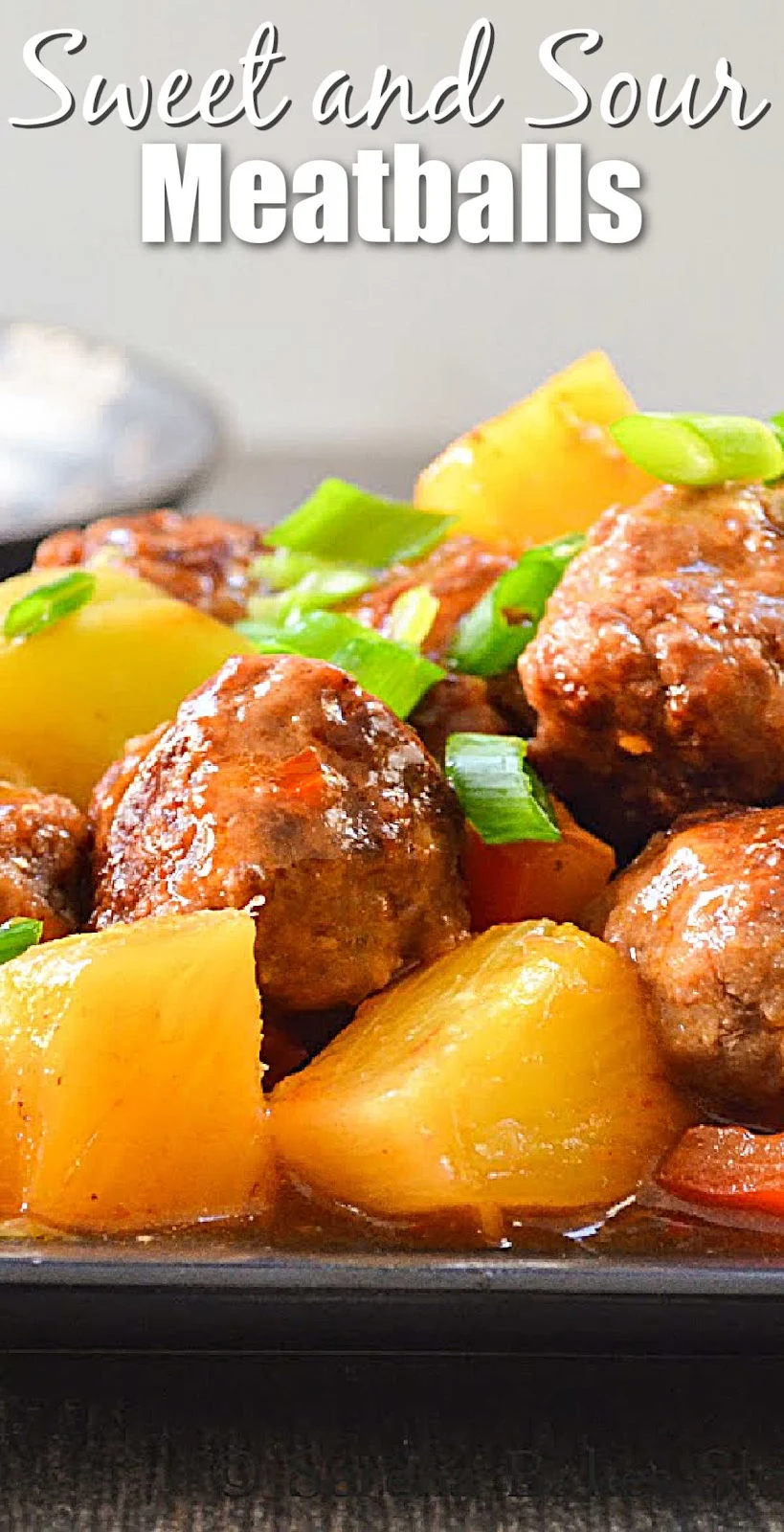 A side photo of Sweet and Sour Meatballs with bell pepper and pineapple on a black plate. White text at the top of the photo Sweet and Sour Meatballs.