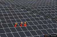 Workers walk among newly installed solar panels at a solar power plant in the Zhouquan township of Tongxiang, Zhejiang province. (Credit: Reuters) Click to Enlarge.