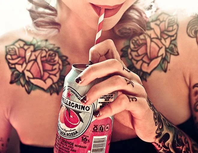 Chica bebiendo refresco con tatuajes en los dedos