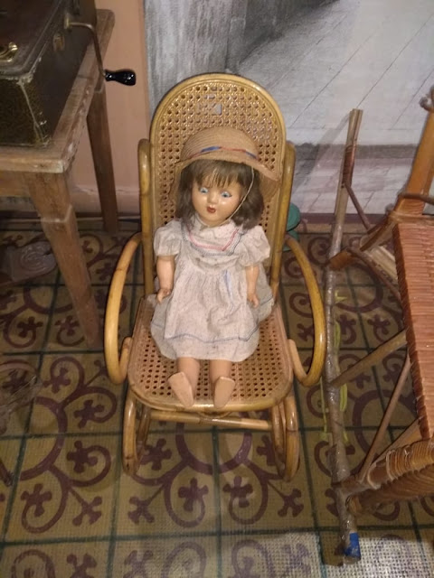 la imagen muestra una muñeca sentada en una silla al lado del tocadiscos