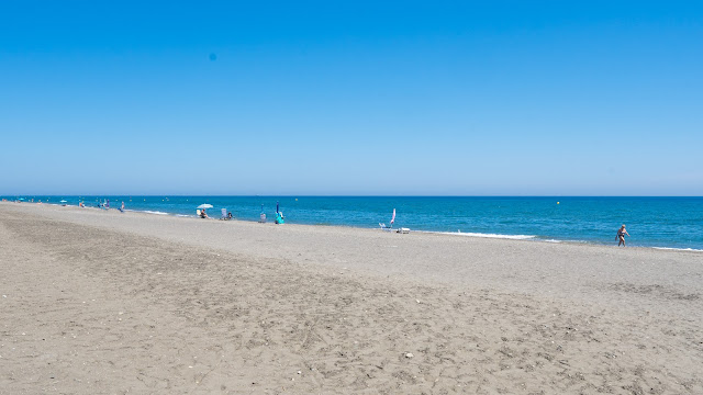 Playa de arena y las azules aguas del mar.