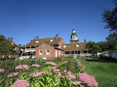 Photo of two story brick house with garden in the foreground and a bright blue sky