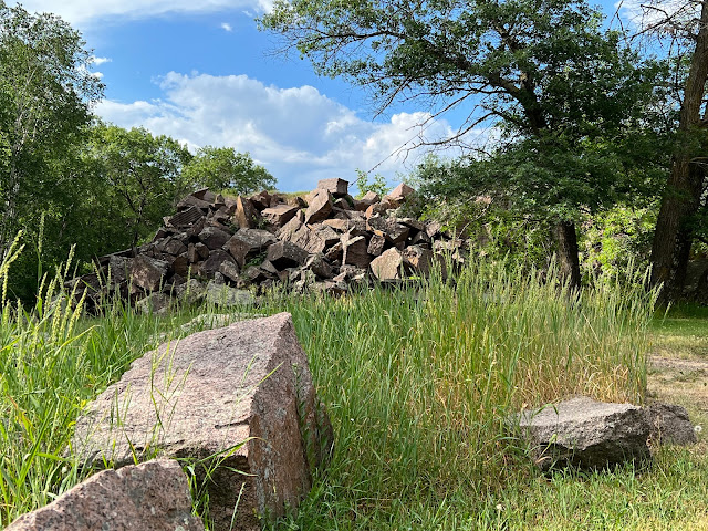 A throw pile of granite rocks emerges above the tall wild grass at  Quarry Park and Nature Preserve in St. Cloud, Minnesota.