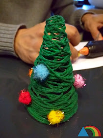 Árbol de Navidad hecho con lana verde y cola, adornado con pompones de colores