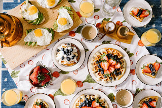 multiple plates of breakfast foods - egg on toast, waffle and fruit