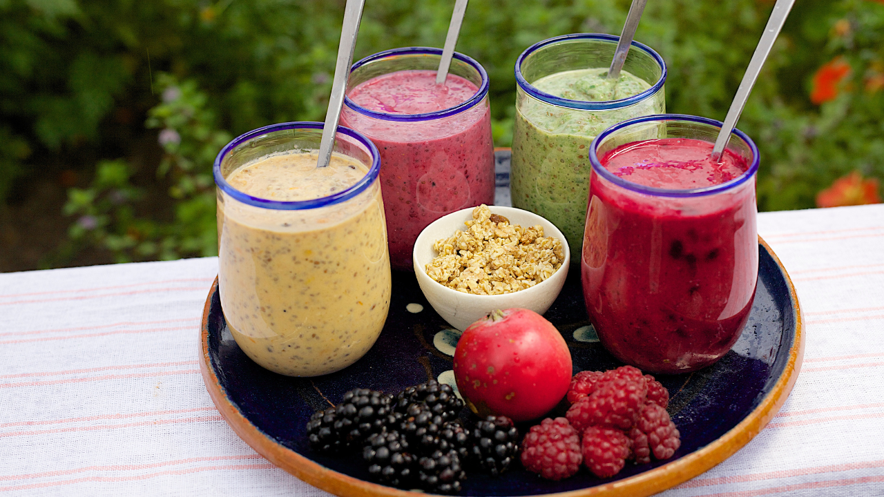 various fruit juices are on a blue plate with straws - image 2