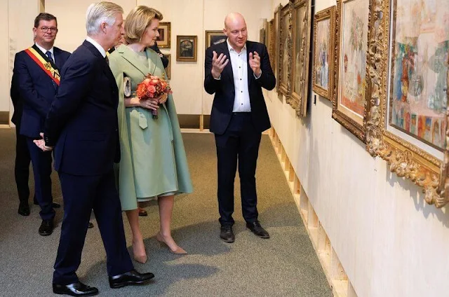 Queen Mathilde wore a sea green wool cape coat and sea green midi dress by Natan. Belgian painter James Ensor