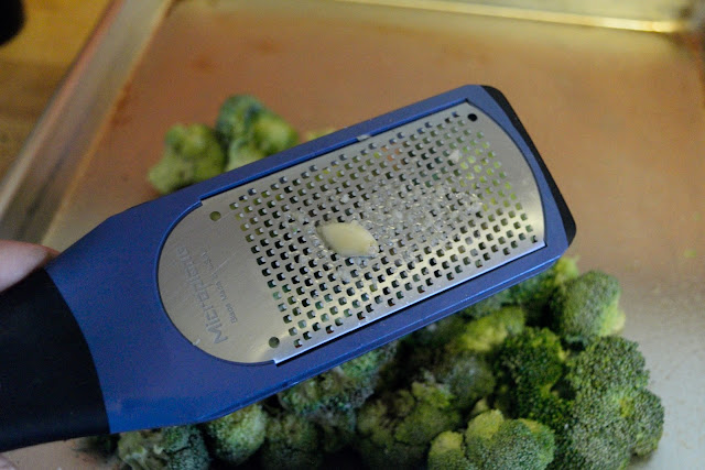 Garlic being grated on a microplane over the garlic.