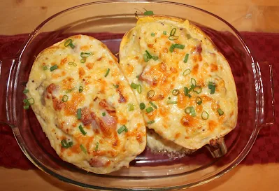 Two halves or finished baked ham and cheese spaghetti squash boats topped with green onions.