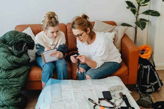 Um mãe- e- seu- filho- analisando- um- mapa- de- viagem- juntos- cercados -por -guias -turísticos -e -itens- de -viagem