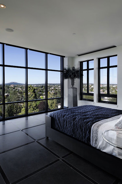 Picture of modern black and white bedroom with glass walls and the view of green hills