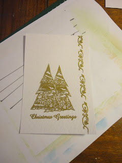 Two trees, "Christmas Greetings" sentiment and line of swirls in gold on white hammered card