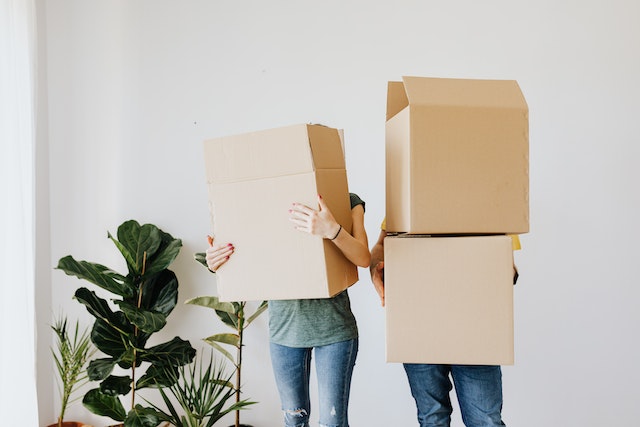 Two people holding boxes and being ready to move.