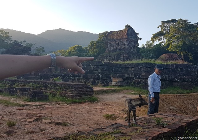 Our guide Ken, a stray dog and us at the My Son site. The deep impression on the ground next to Ken is a bomb crater.