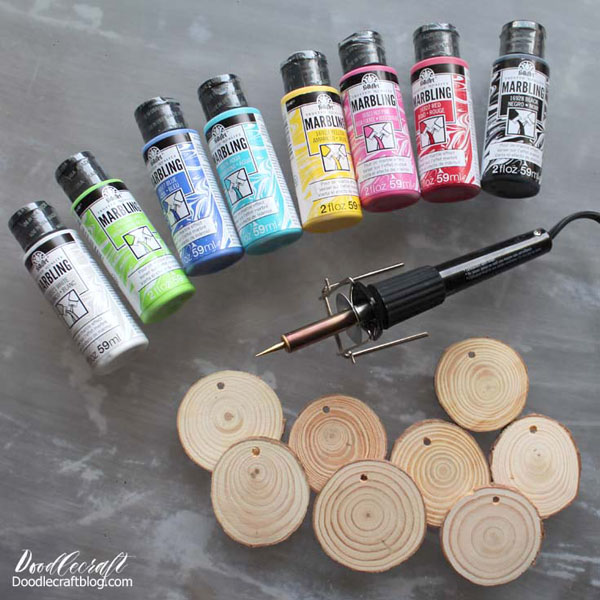 Supplies Needed for Marbled Wood Slice Ornaments: Wood Slices Twine to tie them off Small disposable cups Disposable work surface Plaid Marbling Paints in all the colors! Wood Burning Set (optional) Gold Brush Lettering Paint/paintbrush (optional)