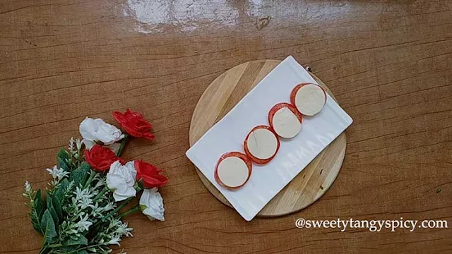 An aesthetically pleasing Caprese salad on a plate, featuring slices of ripe red tomatoes arranged in a neat pattern. On top of each tomato slice, alternating pieces of fresh mozzarella cheese are delicately placed to create a visually appealing arrangement. The contrasting colors and textures of the tomatoes and mozzarella come together, forming a harmonious and appetizing display. This meticulous layering technique elevates the presentation of the salad, promising a delightful feast for both the eyes and palate