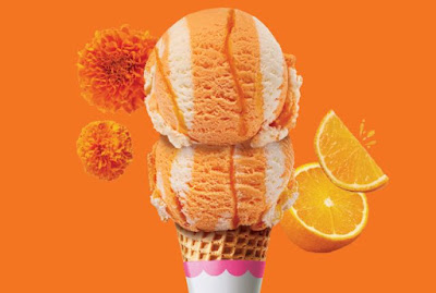 A double scoop of Baskin-Robbins Marigold Dreamsicle ice cream in a cone.