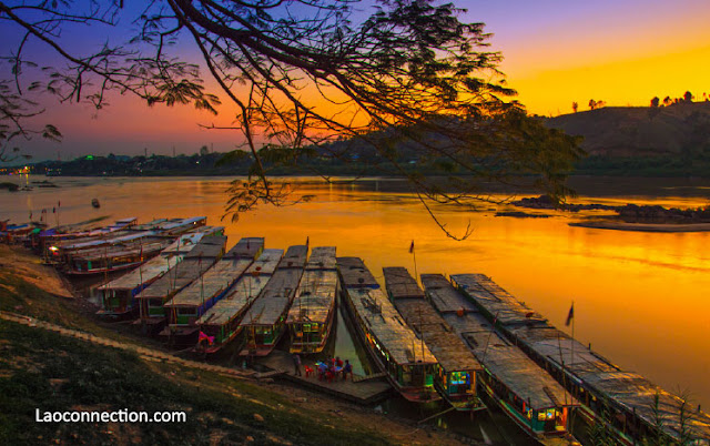 Boats dock as the sun sets over Huayxai