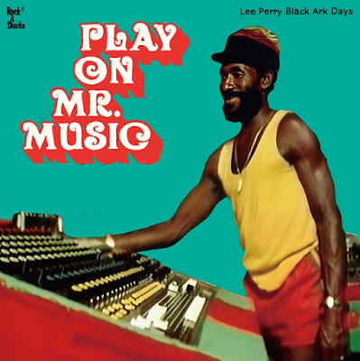 Reggae producer Lee Perry is shown smiling as he adjusts some of the knobs on a recording mixing deck.