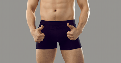 Model in blue boxer shorts making a thumbs up gesture at waist level.