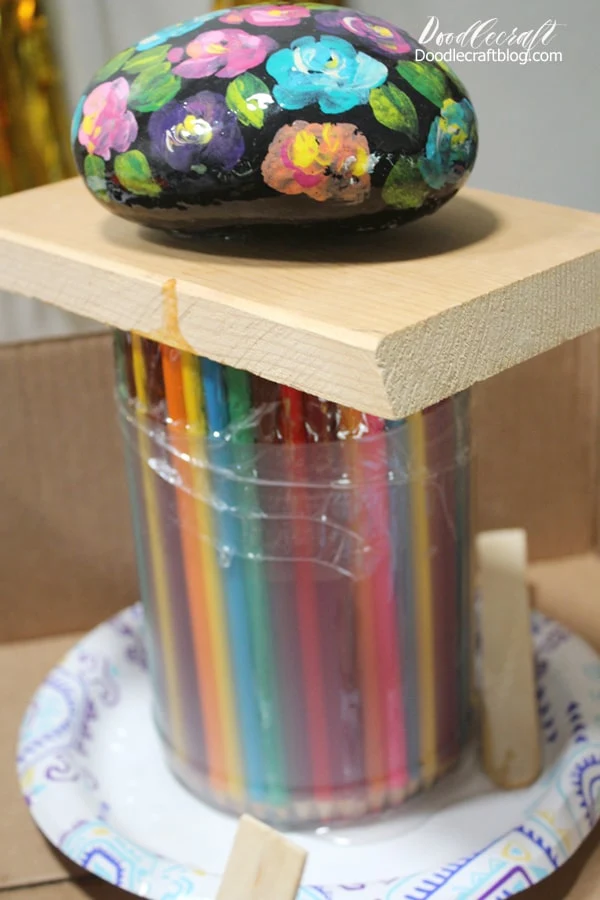 Then I placed a piece of scrap wood and a rock on top to keep the colored pencils from floating. Now just let the resin cure and harden for a few days.