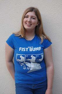 Meagan wearing a blue t shirt with text "How to Fist Bump" and a diagram displaying Hiro and Baymax from Big Hero 6 learning how to fist bump