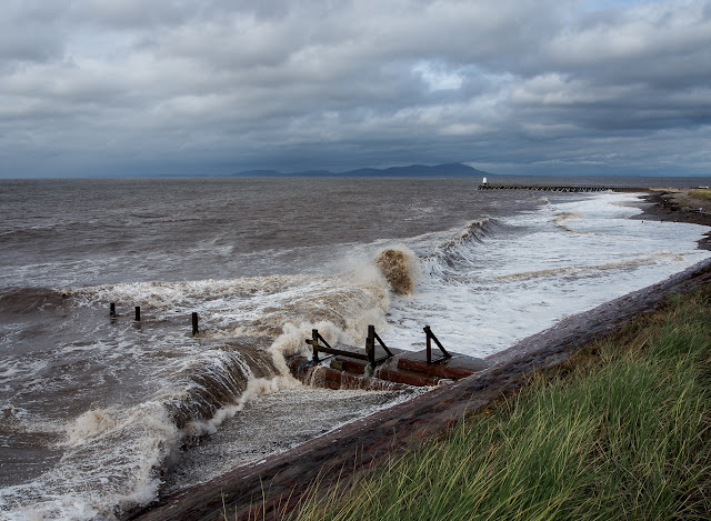 Photo of a large wave rolling in over the groyne on Maryport beach