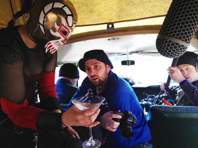 A Mexican wrestler holding a martini inside a Volkswagen van during a flim shoot.